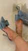 Model wearing denim bow detailed heel mules