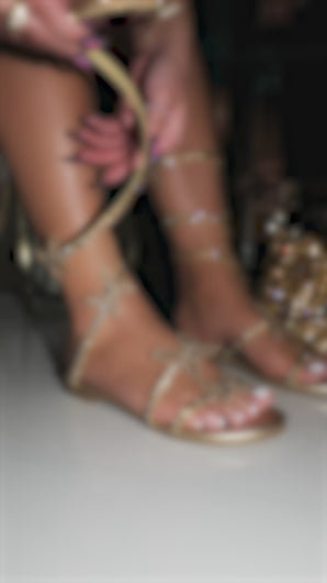 Model wearing gold embellished coil sandals