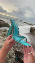 Load and play video in Gallery viewer, Model holding aqua embellished heel by the ocean

