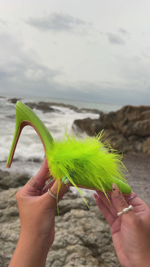 Model holding green feather embellished pump mule by the ocean video