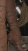 Model wearing gold heels with rhinestone embellished lace up strap closures